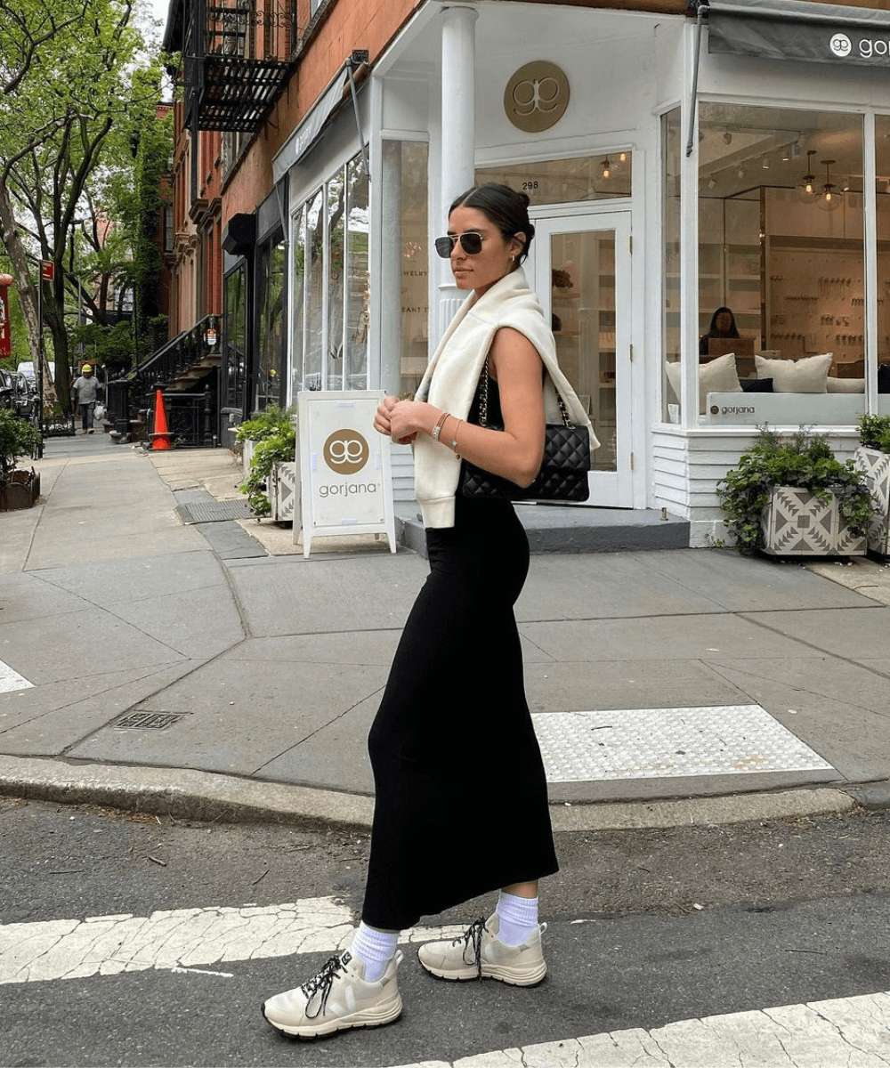 @jennaevangelia - vestido longo preto, tênis vert e suéter amarrado nos ombros - tênis tendência - verão - mulher de óculos em pé na rua - https://stealthelook.com.br