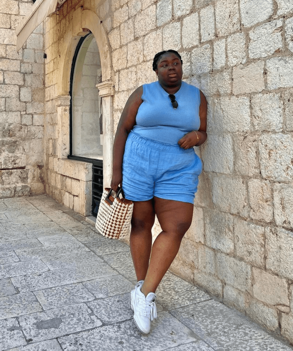 Abisola Omole - conjunto de shorts e regata azul e tênis branco - looks fresquinhos - verão - mulher negra em pé na rua - https://stealthelook.com.br