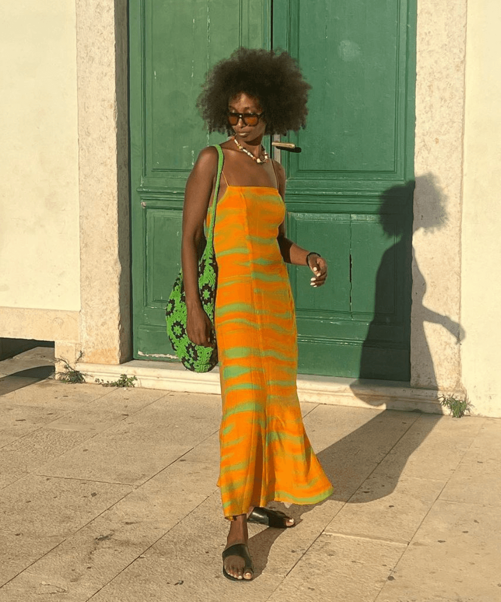 @monamali_ - vestido longo amarelo estampado, óculos e bolsa de crochê verde - looks fresquinhos - verão - mulher negra de óculos em pé na rua - https://stealthelook.com.br