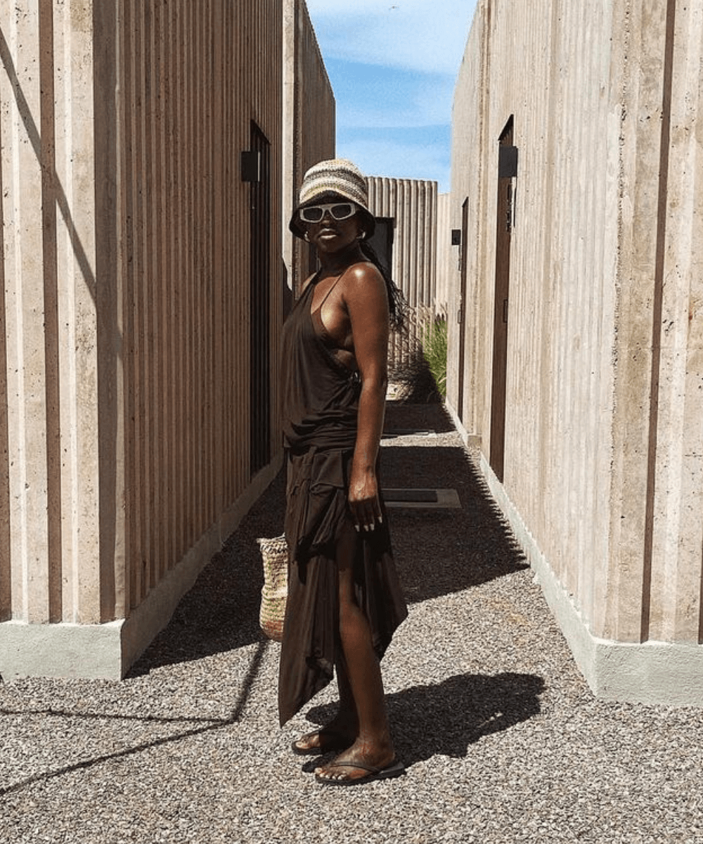 Tahirah Hairston - vestido marrom, biquíni marrom, óculos e bucket hat verde - looks fresquinhos - verão - mulher negra andando na rua usando óculos de sol - https://stealthelook.com.br
