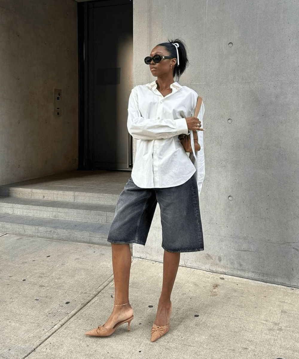 Chanel Mckinsie - bermuda jeans, camisa branca e slingback bege - looks fresquinhos - verão - mulher negra usando óculos em pé na rua - https://stealthelook.com.br