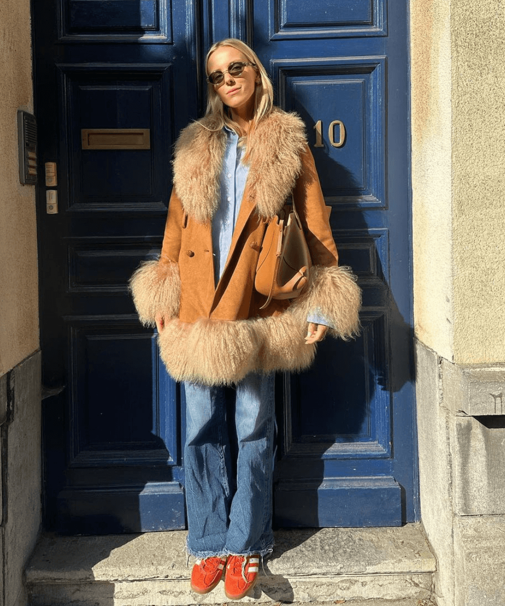 Josefien L. G. Weyns - calça jeans, tênis laranja e casaco penny lane - tendência do inverno 2024 - inverno - mulher loira em pé na rua usando óculos de sol - https://stealthelook.com.br