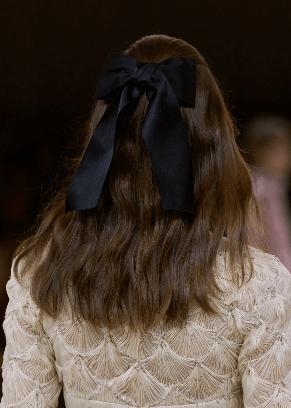 Chanel S/S 2024 - N/A - tendências polêmicas - primavera - foto do cabelo de uma modelo com um laço preto preso a ele - https://stealthelook.com.br