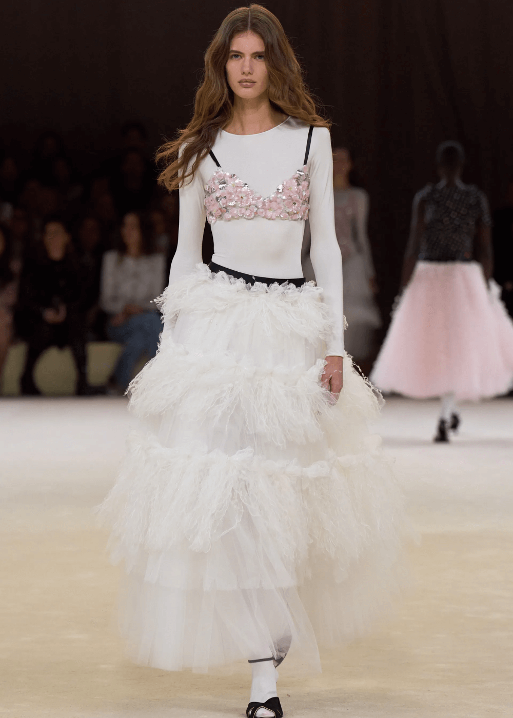 Chanel S/S 2024 - macacão branco e saia de tule rosa - tendências polêmicas - primavera - modelo andando na passarela - https://stealthelook.com.br