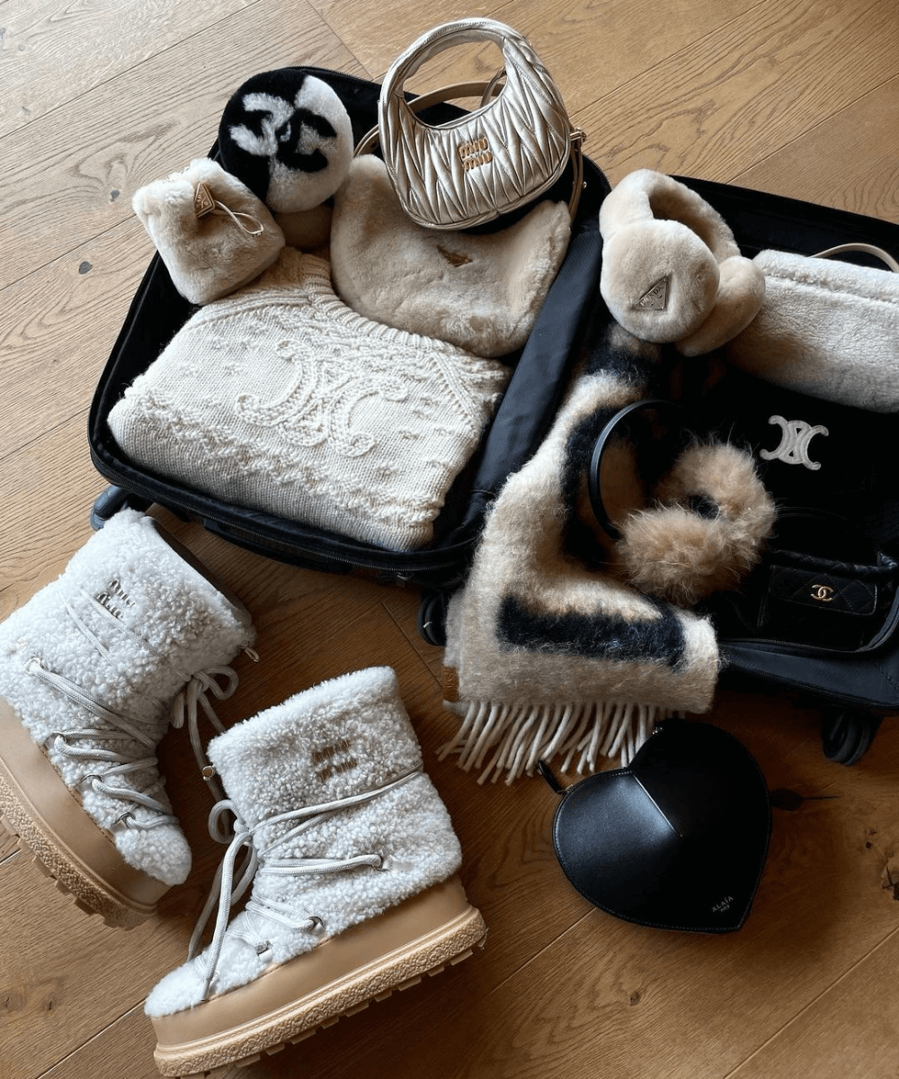 @leoniehanne - N/A - mala de viagem - inverno - foto de uma mala preta aberta no chão com diversos itens de inverno em tons de bege - https://stealthelook.com.br