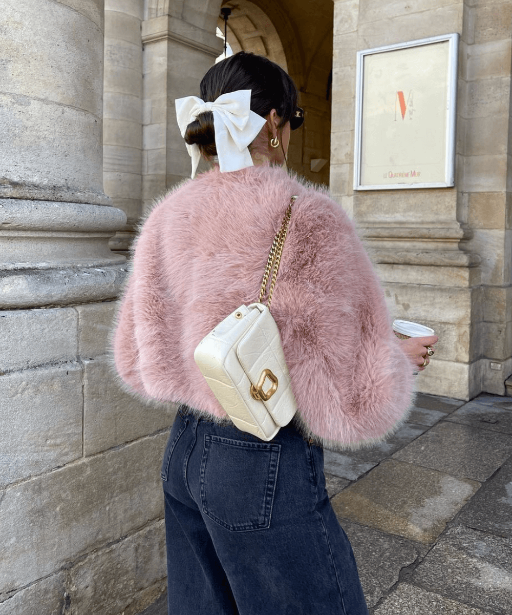 @florettenacer - casaco rosa peludo, calça jeans, laço branco no cabelo - laços - inverno - mulher de costas andando na rua - https://stealthelook.com.br