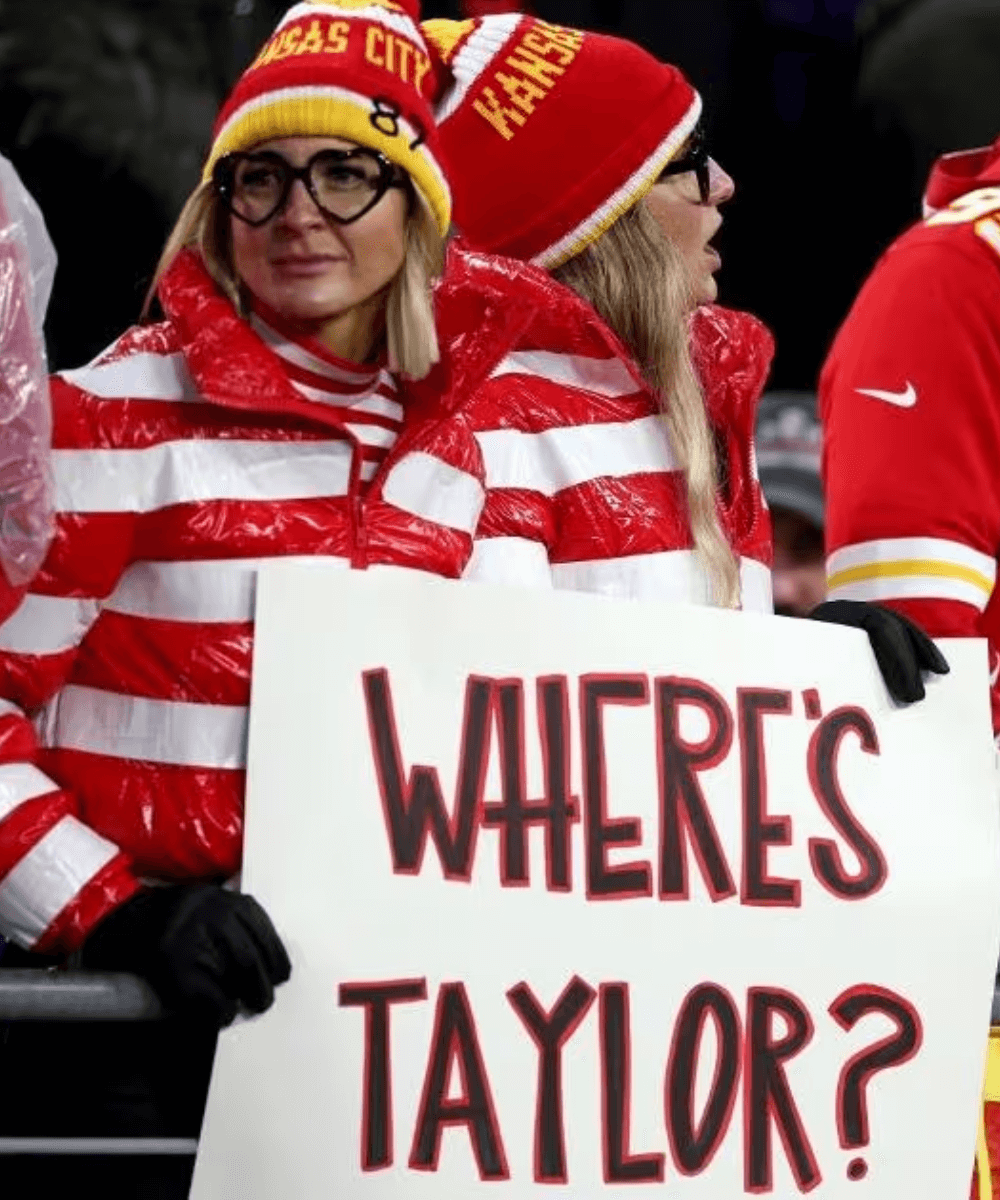 Fãs do Kansas City Chiefs - casaco listrado branco e vermelho, gorro vermelho e óculos rendondo preto - Super Bowl 2024 - inverno - mulher loira segurando um cartaz escrito 'Where's Taylor?