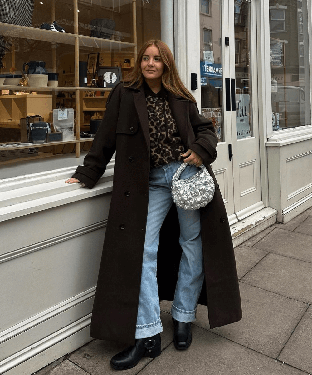 @rebeccaferrazwyatt - calça jeans, bota preta, camisa de oncinha e casaco preto longo - tendência do inverno - inverno - mulher em pé na rua olhando para o lado - https://stealthelook.com.br