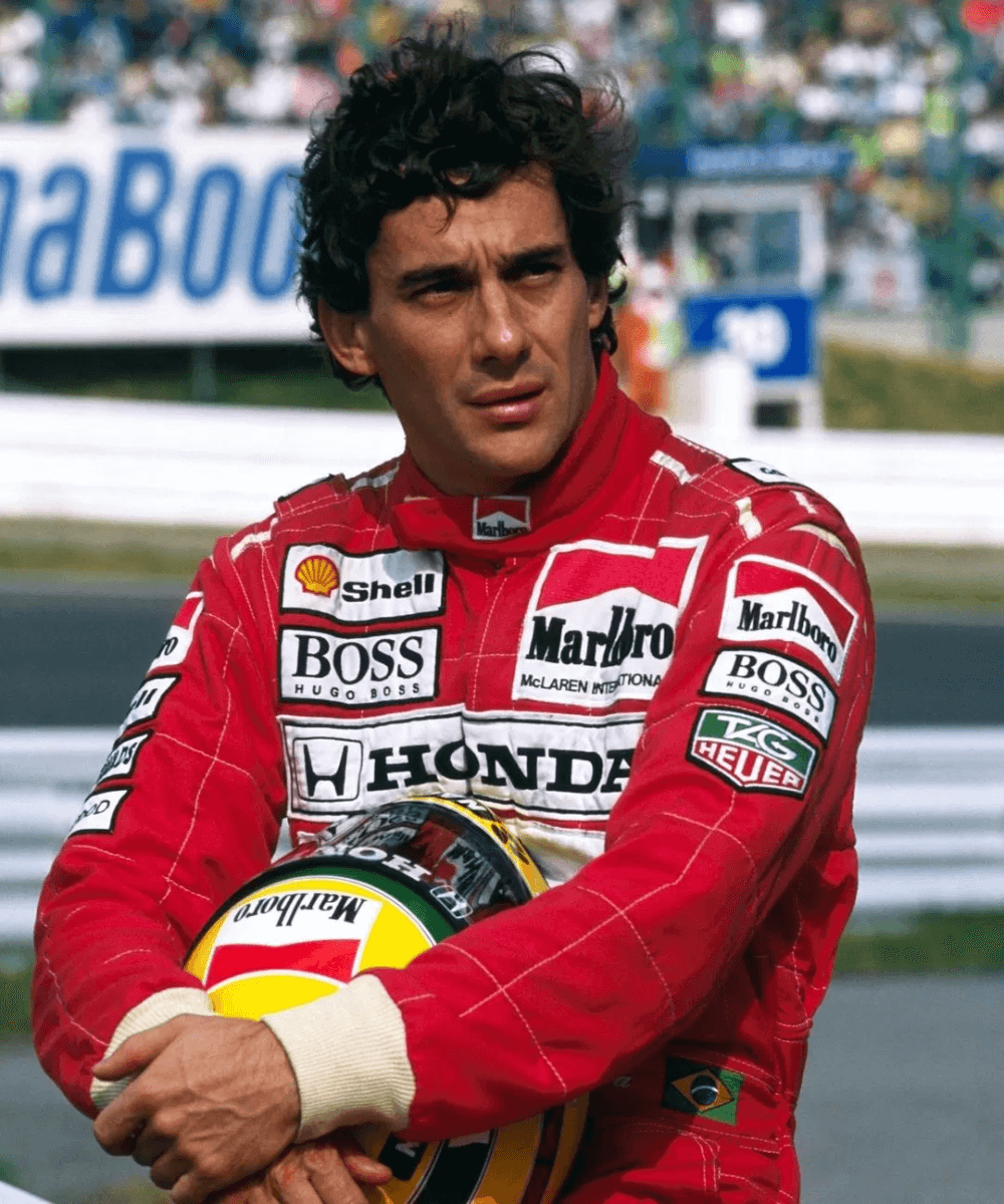 Ayrton Senna - macacão de fórmula 1 vermelho - Fórmula 1 - inverno - homem sentado segurando um capacete - https://stealthelook.com.br