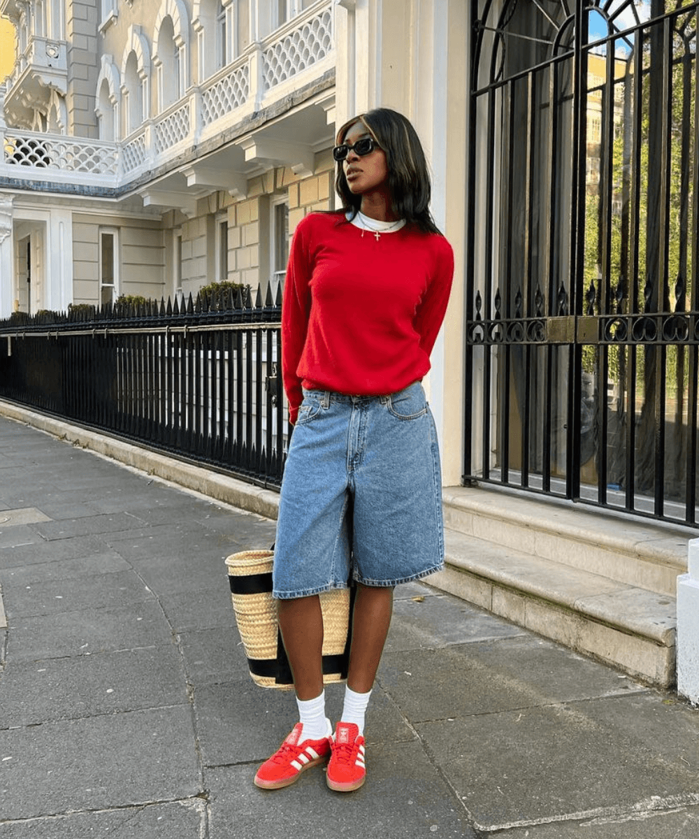@georgia_3.0 - bermuda jeans, tênis vermelho e tricot vermelho - sapato vermelho - outono - mulher negra em pé na rua usando óculos de sol - https://stealthelook.com.br