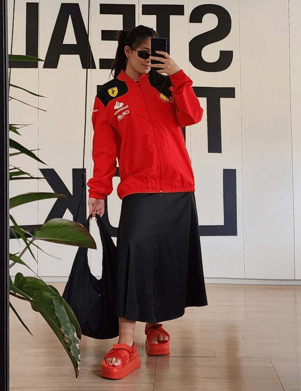 Izabela Suzuki - saia midi preta, jaqueta vermelha da ferrari, papete ryder e bolsa preta - Fórmula 1 - verão - mulher asiática tirando foto no espelho - https://stealthelook.com.br