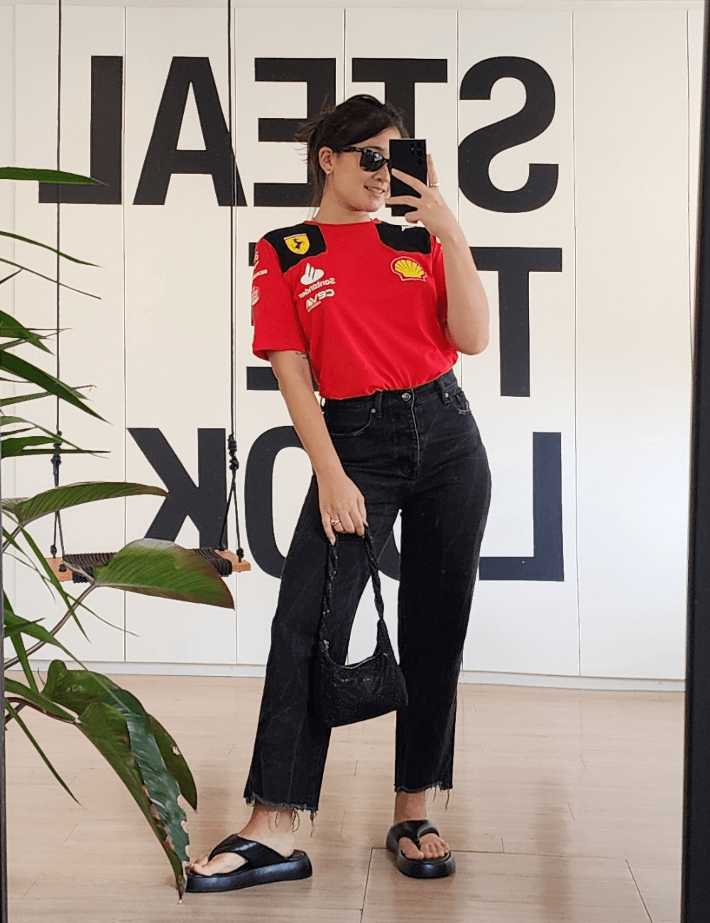 Izabela Suzuki - calça jeans preta, blusa vermelha da ferrari, óculos e bolsa preta - Fórmula 1 - verão - mulher asiática tirando foto no espelho - https://stealthelook.com.br