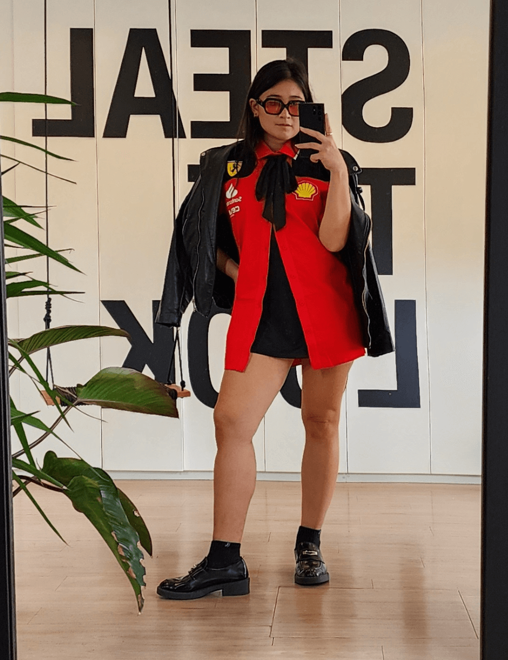 Izabela Suzuki - blusa vermelha ferrari, laço preto, minissaia preta, mocassim e jaqueta de couro preta - Fórmula 1 - verão - mulher asiática tirando foto no espelho - https://stealthelook.com.br