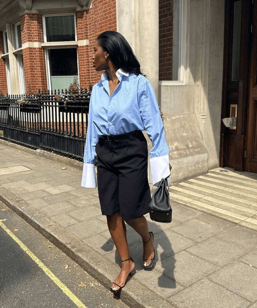 @nlmarilyn - bermuda preta de alfaiataria, sandálias e camisa social azul listrada - looks formais - verão - mulher negra andando na rua - https://stealthelook.com.br