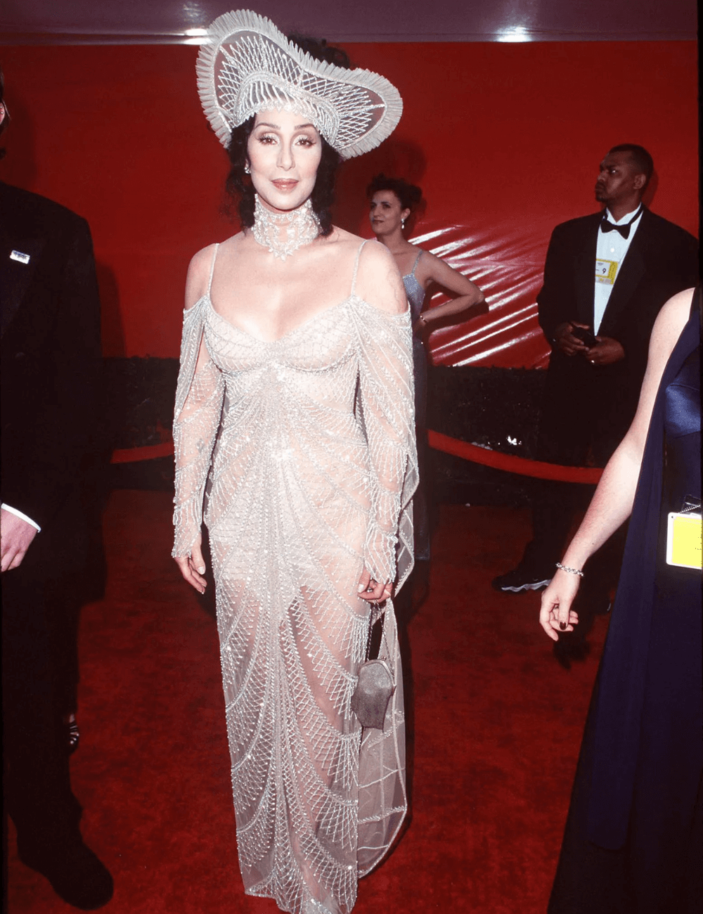 Cher - roupa longa branca com aplicações prateadas brilhantes e adereço na cabeça - Looks da Cher - verão - mulher em pé no tapete vermelho - https://stealthelook.com.br
