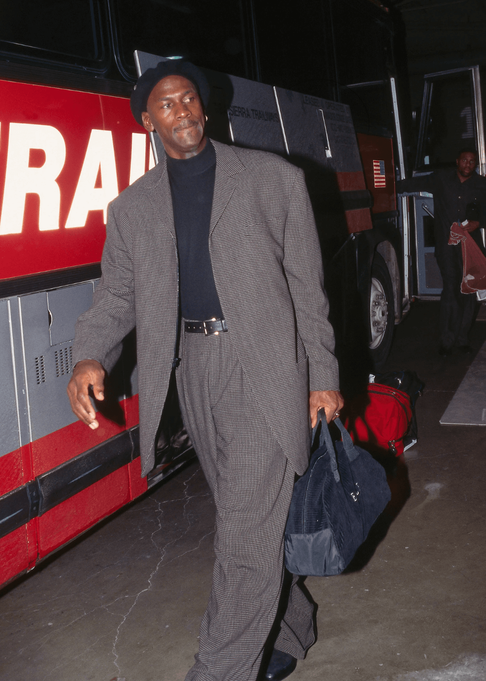 Michael Jordan - terninho cinza, boina e mala preta - moda e esporte - inverno - homem negro de boina andando com uma mala nas mãos - https://stealthelook.com.br