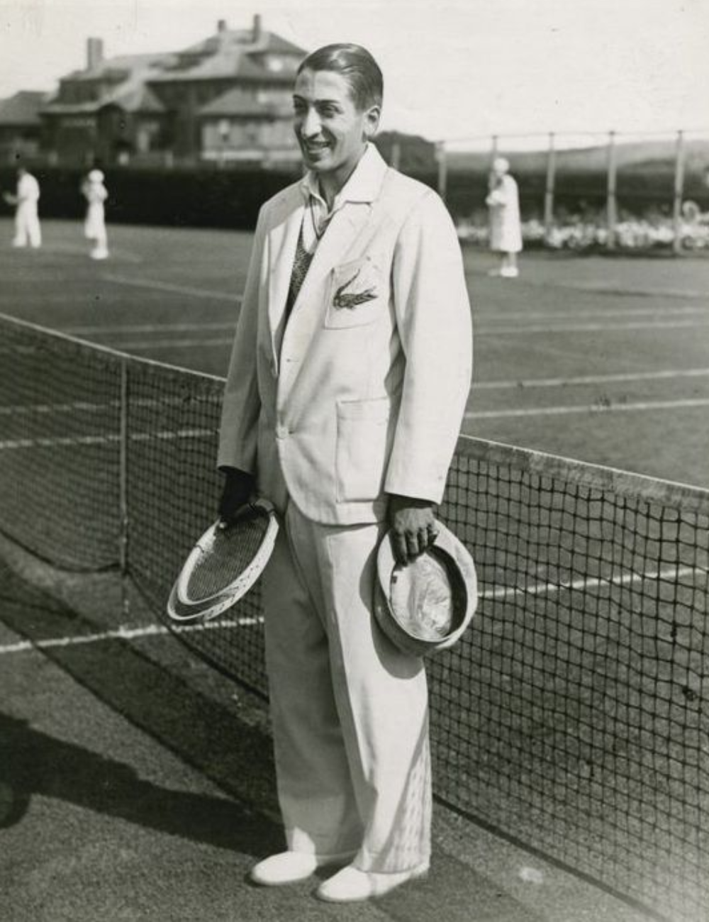 René Lacoste - terno - Moda e tênis - inverno - homem parado em pé segurando uma raquete antiga de tênis - https://stealthelook.com.br