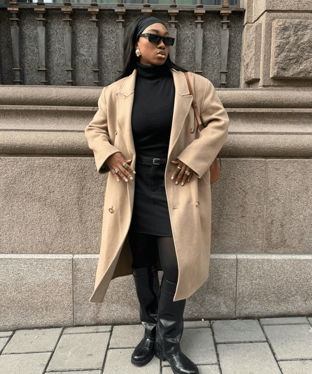 Nnenna Echem - saia, meia-calça, bota de cano longo e casaco longo - sapatos de inverno - inverno - mulher negra em pé na rua usando óculos de sol - https://stealthelook.com.br