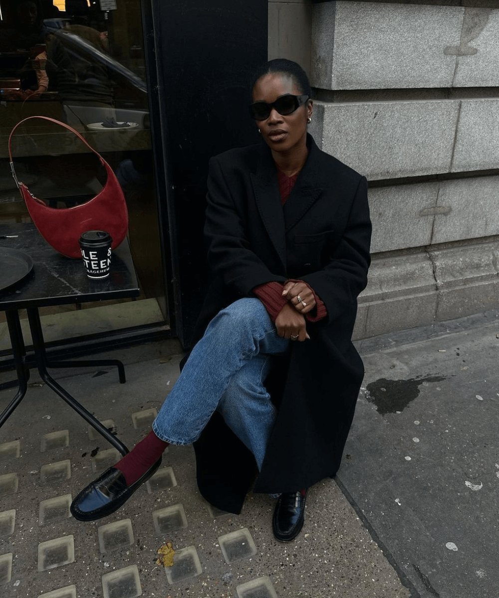 @nlmarilyn - calça jeans, tricot vermelho, meia vermelha e mocassim preto - sapatos de inverno - inverno - mulher negra de óculos usando casaco preto sentada - https://stealthelook.com.br