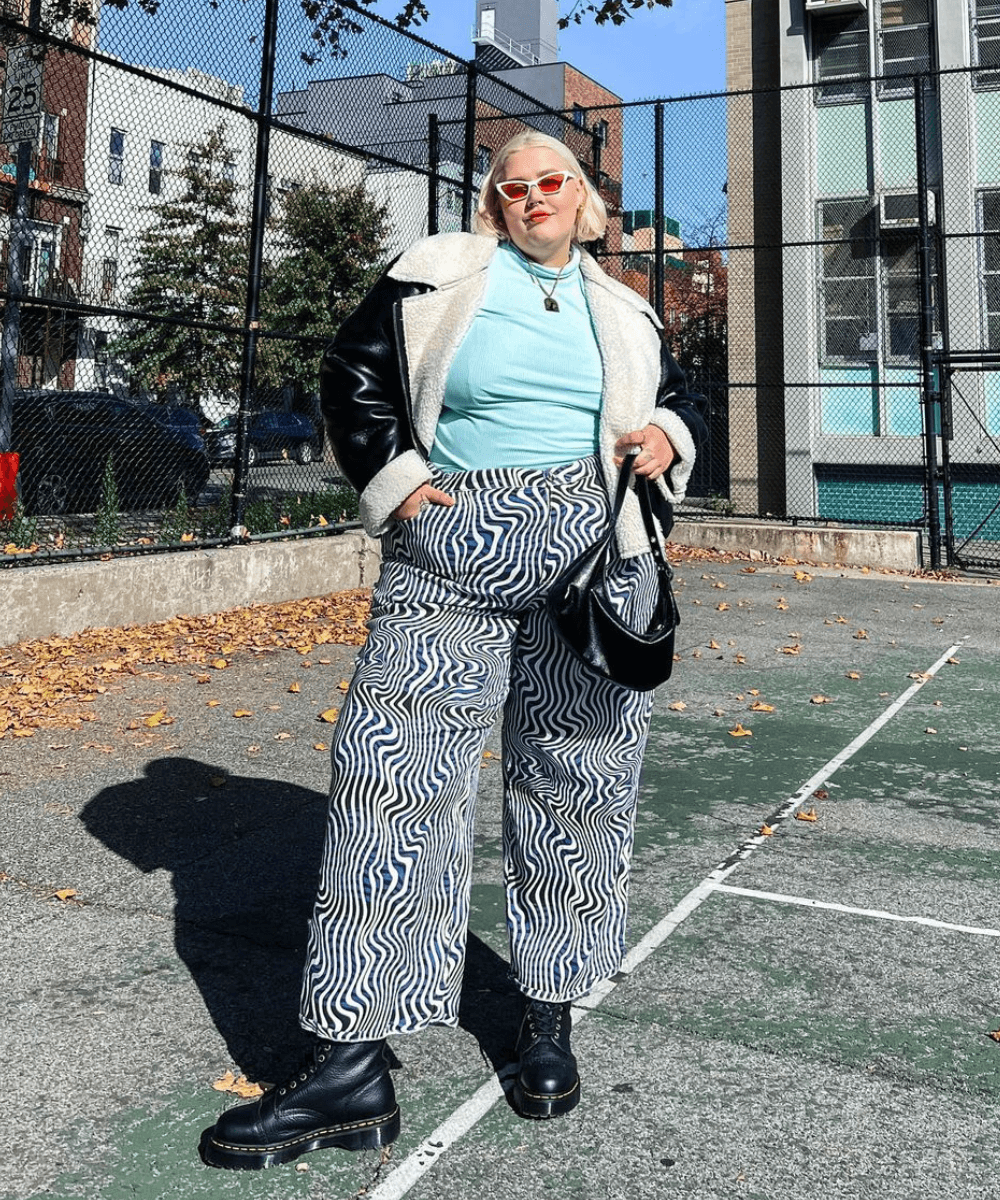 Abby Bible - calça estampada, coturno, tricot azul e jaqueta de couro preta - sapatos de inverno - inverno - mulher loira em pé na rua usando óculos de sol - https://stealthelook.com.br