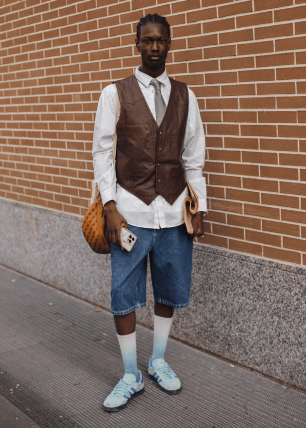 Street Style de Milão - bermuda jeans, colete, meias brancas longas, tênis adidas, camisa e gravata - street style de Milão - inverno - homem negro em pé usando óculos de sol - https://stealthelook.com.br