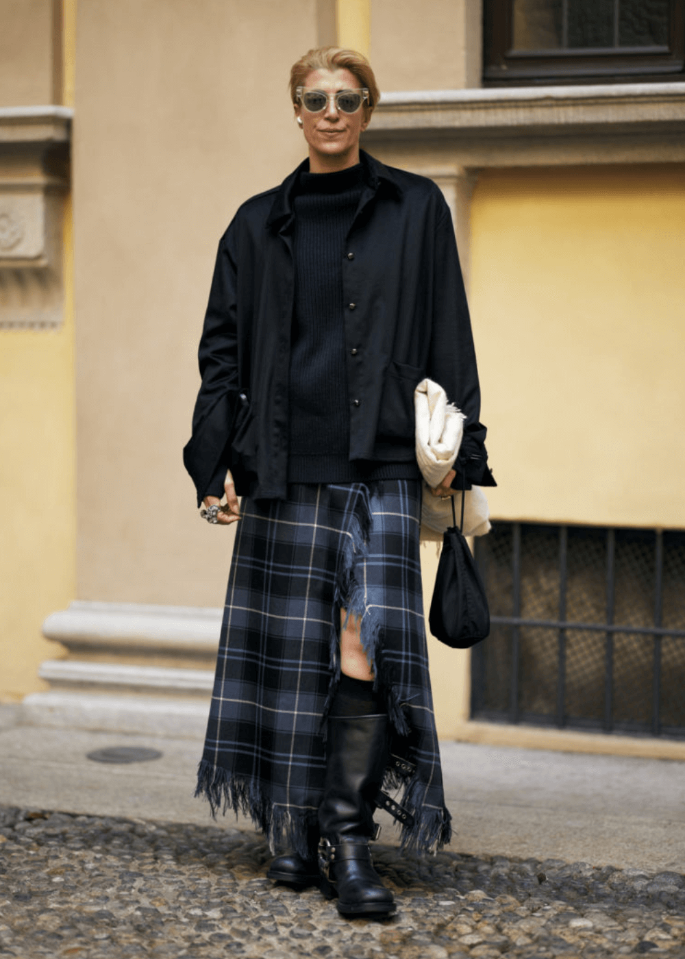 Street Style de Milão - saia longa xadrez, bota, tricot preto e óculos - street style de Milão - inverno - mulher em pé na rua usando óculos de sol - https://stealthelook.com.br