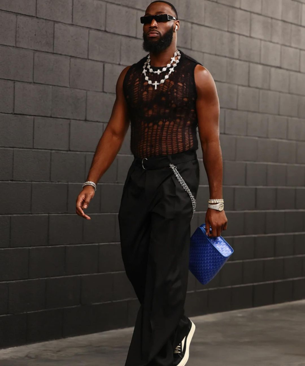 Charles Omenihu - roupa inteira preta - Super Bowl 2024 - inverno - homem negro andando de óculos usando um look inteiro preto e com uma mala nas mãos - https://stealthelook.com.br