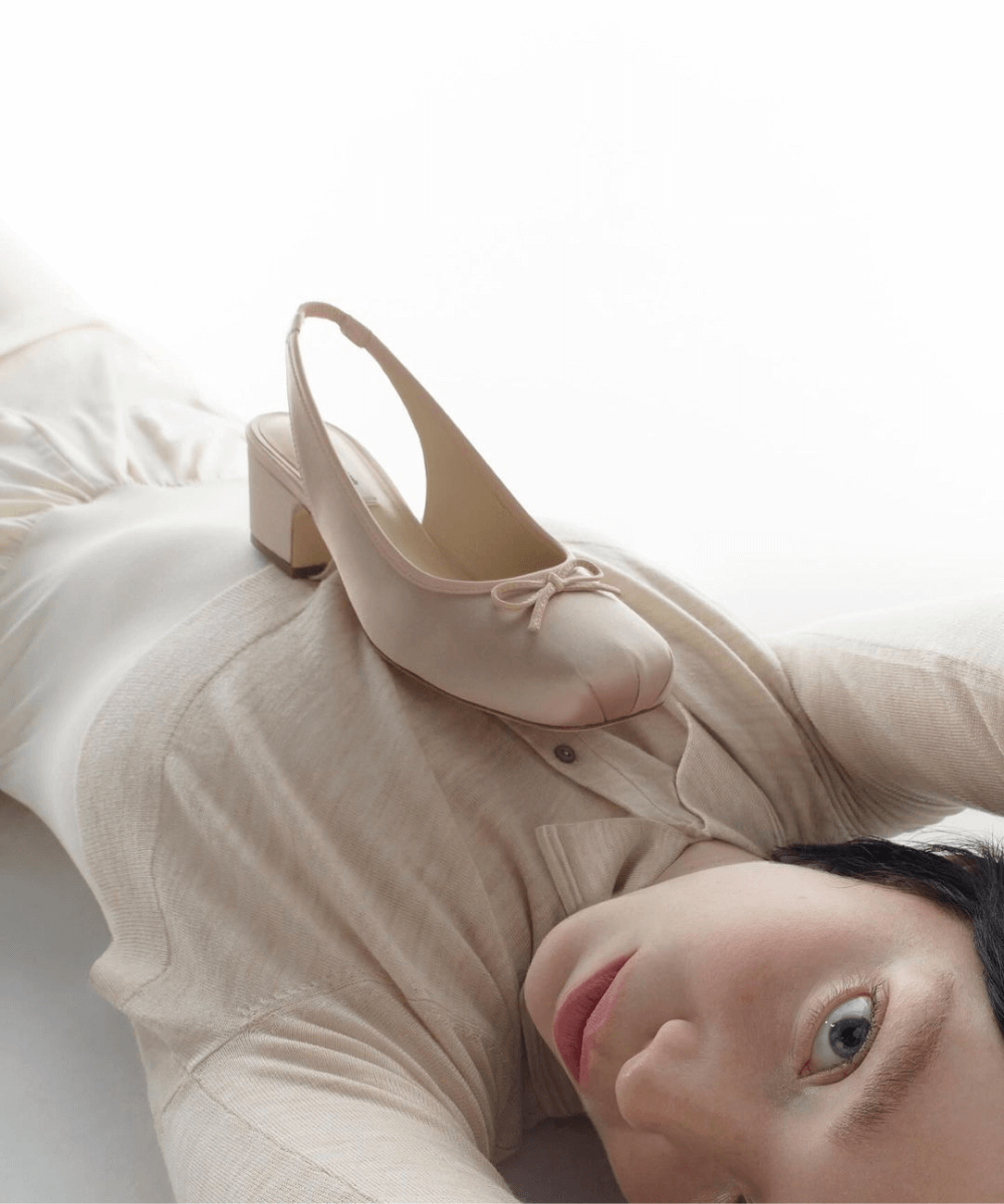 Sandy Liang - blusa branca justa de mangas longas - Sandy Liang - outono - mulher asiática deitada com um sapato rosa bebê de salto em cima - https://stealthelook.com.br