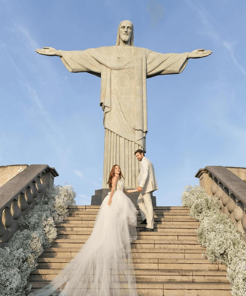 Mari Maria e Rudy Loures - vestido de noiva - vestido de noiva da Mari Maria - verão - casal subindo a escada de mãos dadas no amanhecer no Cristo Redentor - https://stealthelook.com.br