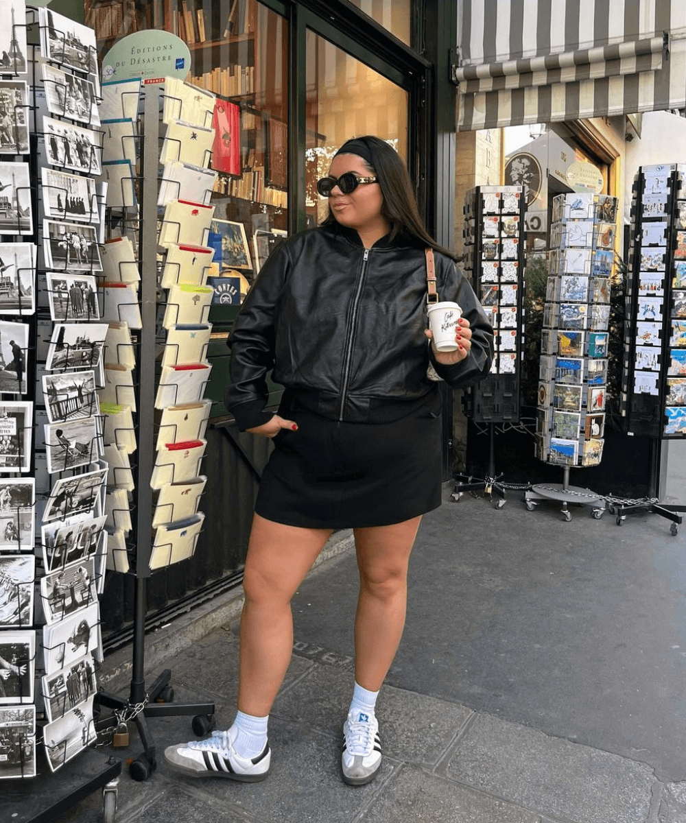 Freya Broni - minissaia preta, tênis adidas, jaqueta preta e óculos de sol - acessório tendência - outono - mulher de óculos em pé na rua - https://stealthelook.com.br