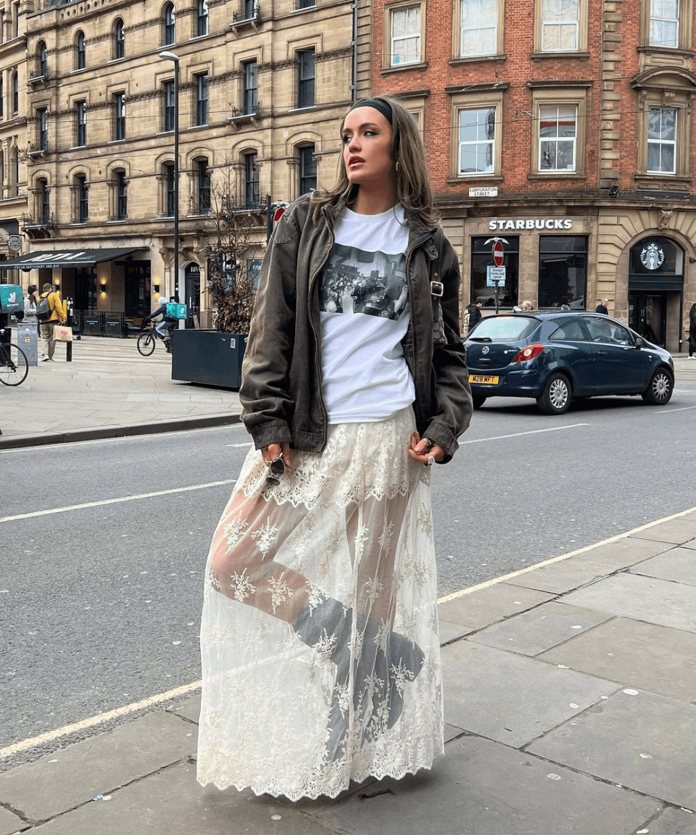 Ellie Robinson - saia transparente branca, t-shirt, jaqueta marrom e botas pretas - acessório tendência - outono - mulher em pé na rua - https://stealthelook.com.br