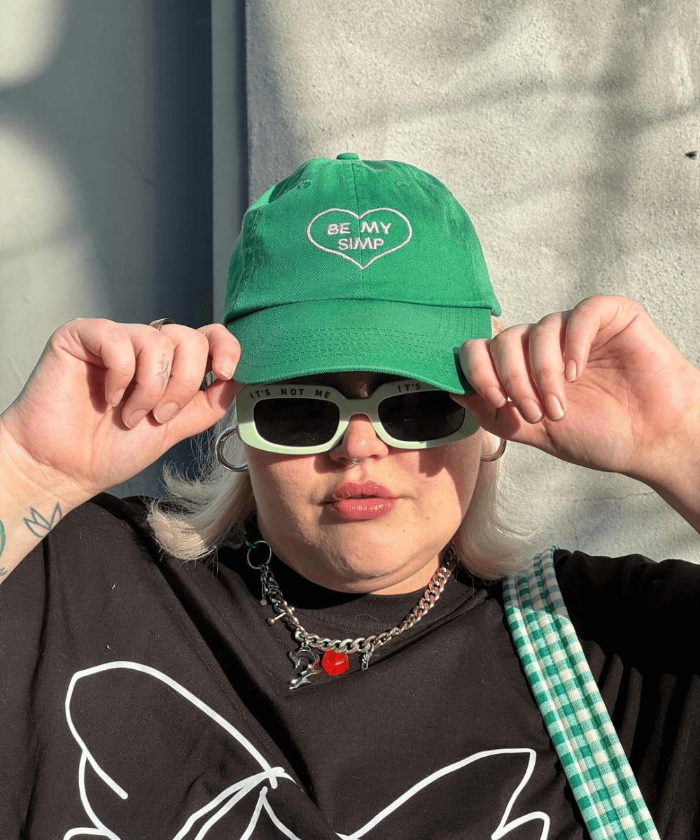 Abby Bible - boné verde e óculos escuros - armário cápsula - verão - close de rosto em uma mulher usando boné verde e óculos escuro - https://stealthelook.com.br