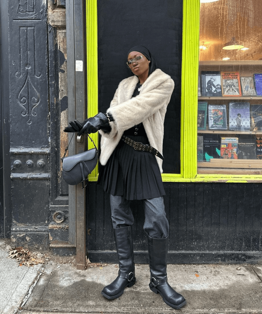 Chanel Mckinsie - calça preta, vestido preto, casaco bege e botas pretas - biker boots - inverno - mulher negra em pé na rua usando óculos de sol - https://stealthelook.com.br