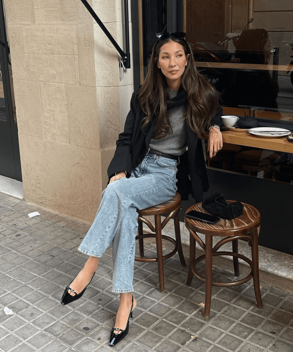 Felicia Akerstrom - calça jeans, slingback preto, camiseta cinza, blazer preto - jeans e camiseta - inverno - mulher sentada em um café na rua - https://stealthelook.com.br