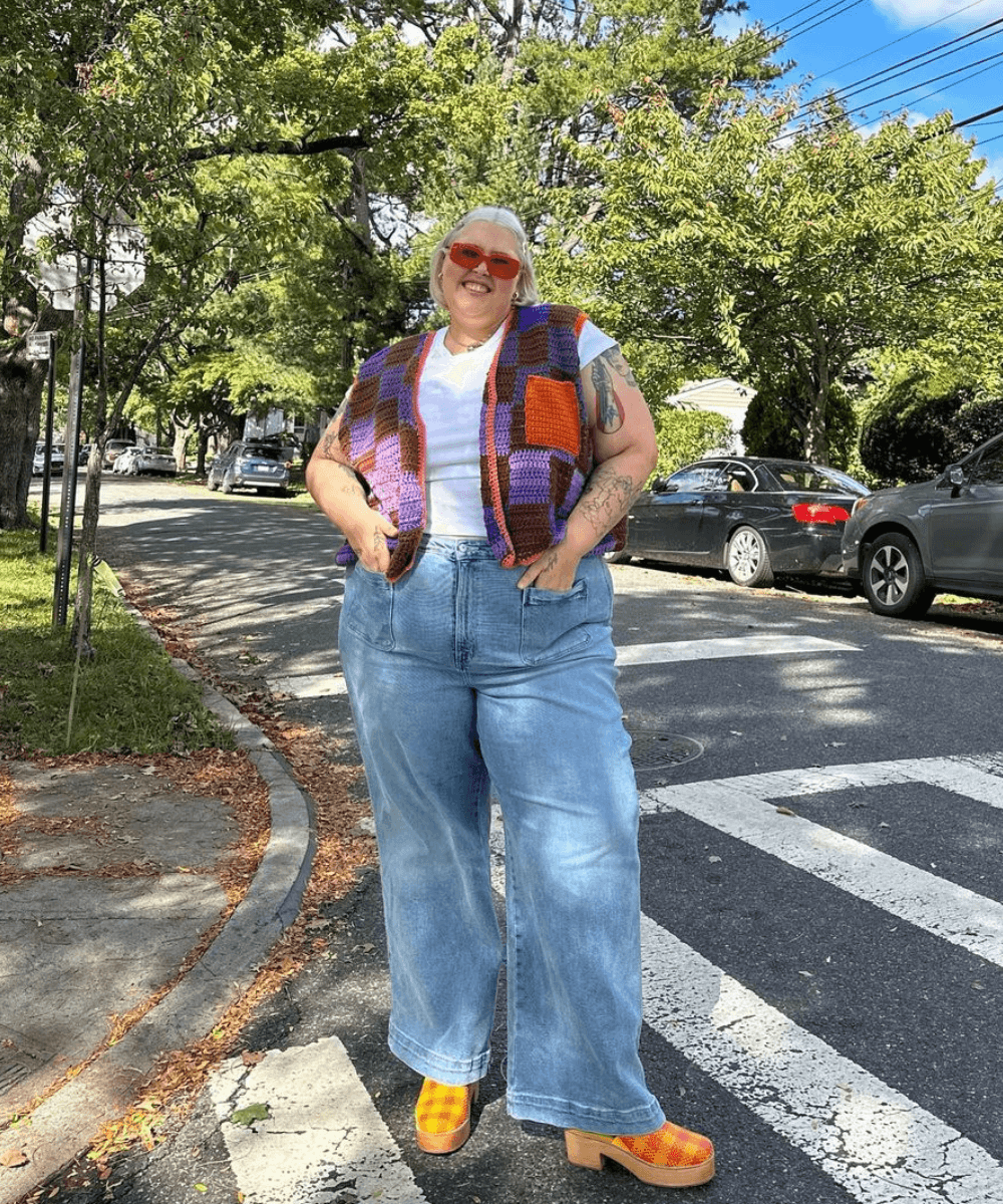 Abby Bible - calça jeans, camiseta branca, colete de tricô colorido e clog laranja - jeans e camiseta - verão - mulher loira em pé na rua usando óculos de sol - https://stealthelook.com.br