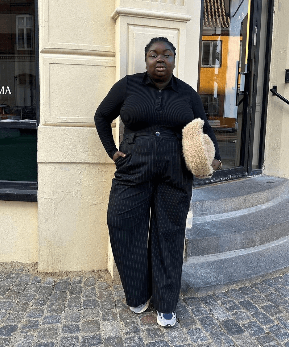 Abisola Omole - calça preta, blusa preta de manga longa e tênis - looks com tênis - outono - mulher negra em pé na rua - https://stealthelook.com.br