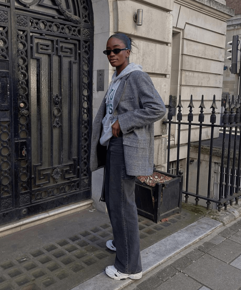 Liv Madeline - calça jeans, tênis, moletom e blazer cinza - looks com tênis - inverno - mulher negra em pé na rua usando óculos de sol - https://stealthelook.com.br