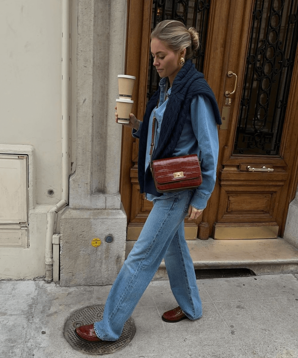 Claire Rose Cliteur - calça jeans, camisa jeans, mocassim e trico preto - looks fáceis - outono - mulher loira de coque andando na rua - https://stealthelook.com.br