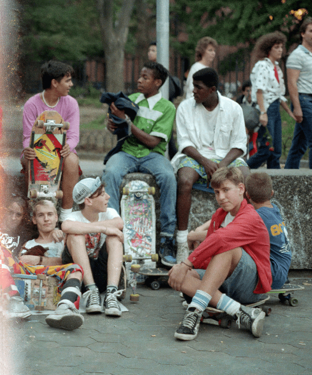 Skatistas durante a década de 80 - roupas diversas - Moda e Skate - verão - pessoas reunidas em uma praça sentadas e andando de skate - https://stealthelook.com.br