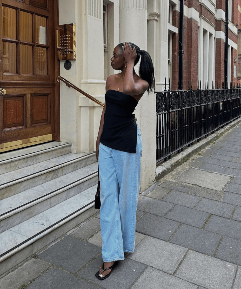 Liv Madeline - calça jeans, blusa preta sem alça e sandálias pretas - tendências do verão - verão - mulher negra em pé na rua - https://stealthelook.com.br