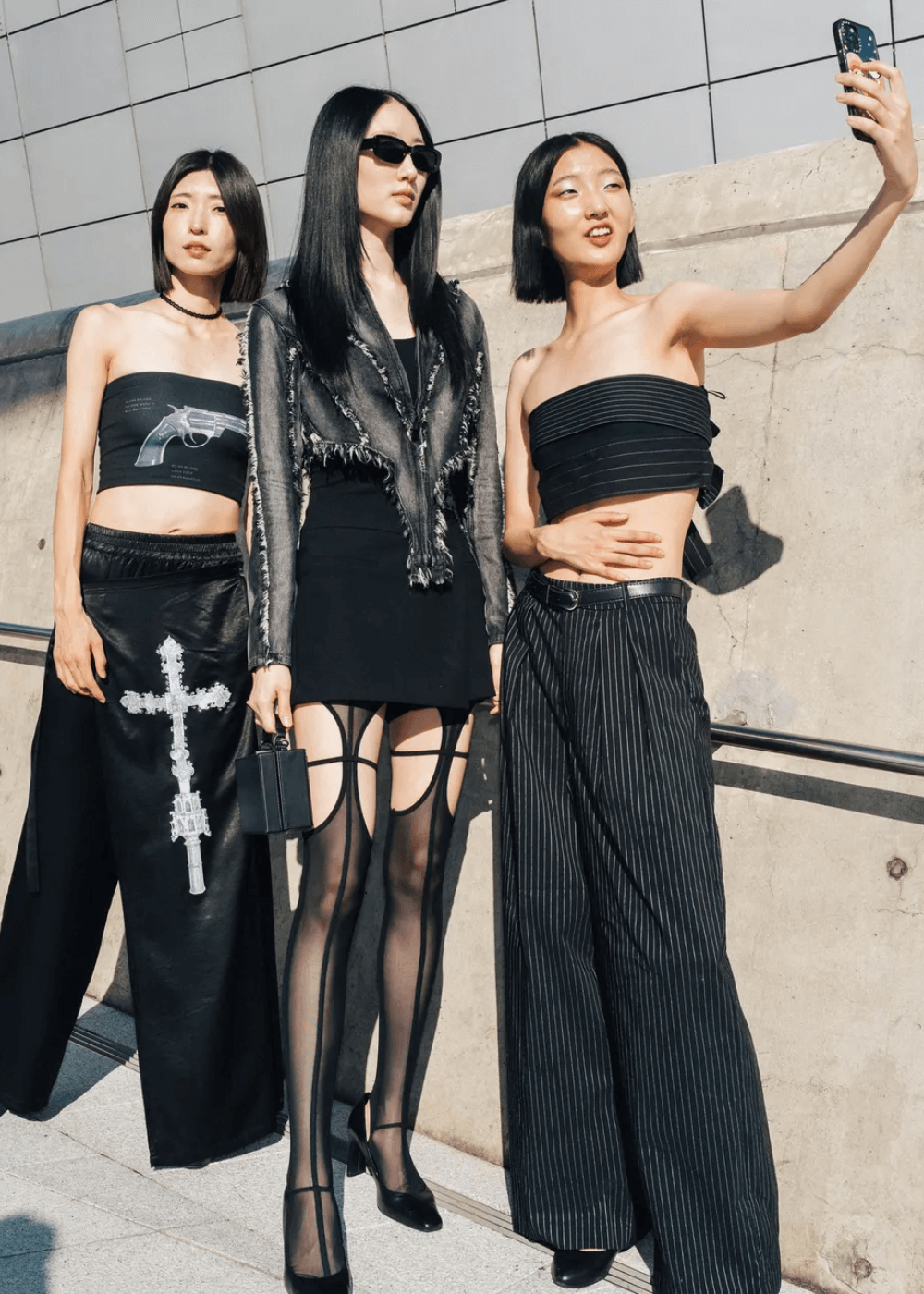 Street Style asiático - roupas pretas diversas - Street Style asiático - primavera - três mulheres asiáticas em pé usando looks pretos tirando uma foto na ru - https://stealthelook.com.br