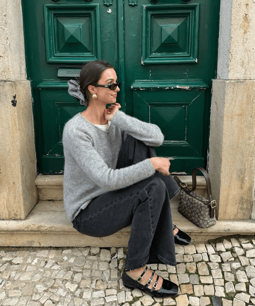 @laraaceliaa - calça jeans, sapato mary jane preto, tricot cinza e óculos - looks de outono - outono - mulher sentada em uma escada na rua - https://stealthelook.com.br
