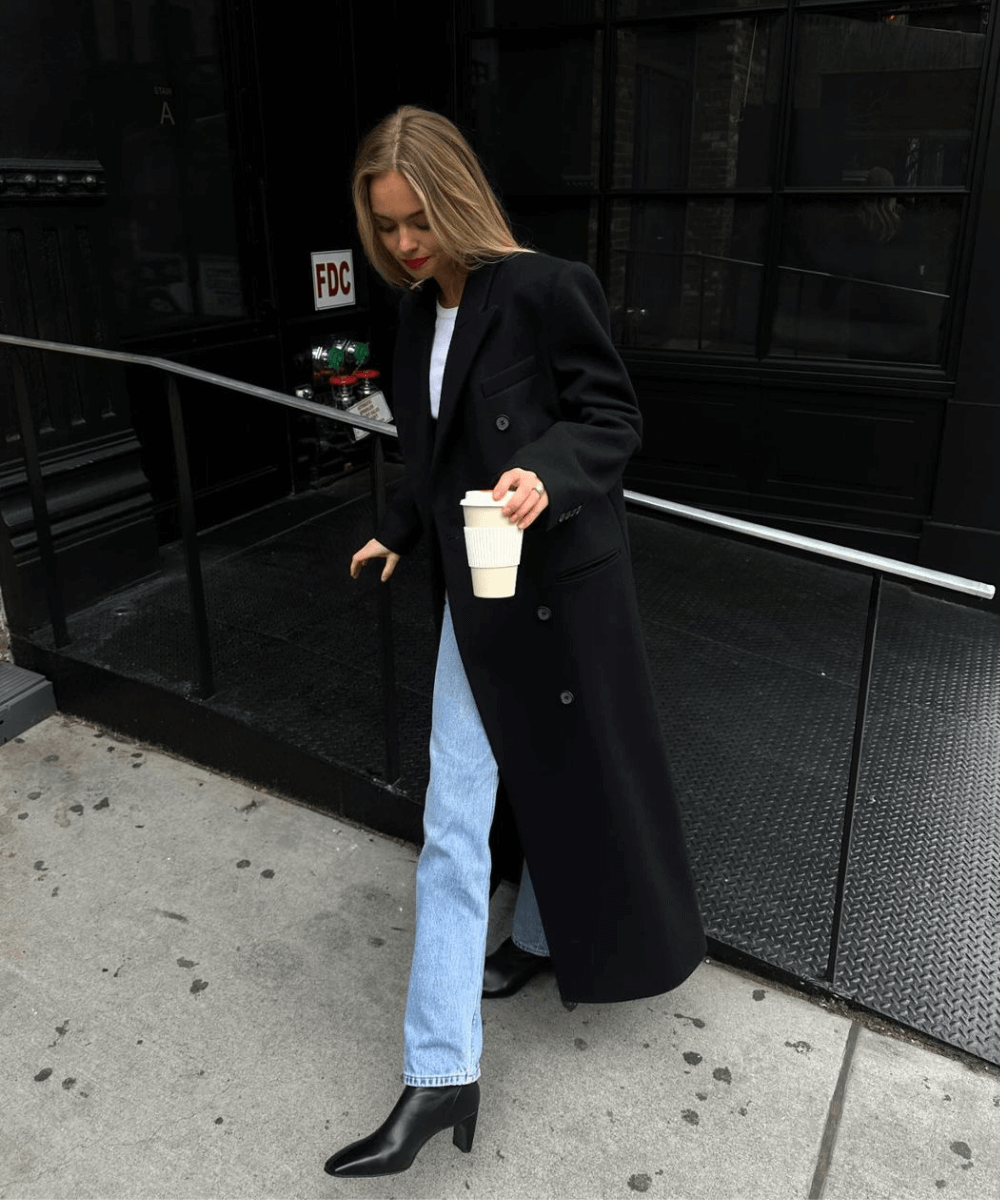 Claire Rose Cliteur - calça jeans, regata branca, bota e sobretudo preto - como usar sobretudo - inverno - mulher loira em pé na rua usando batom vermelho - https://stealthelook.com.br