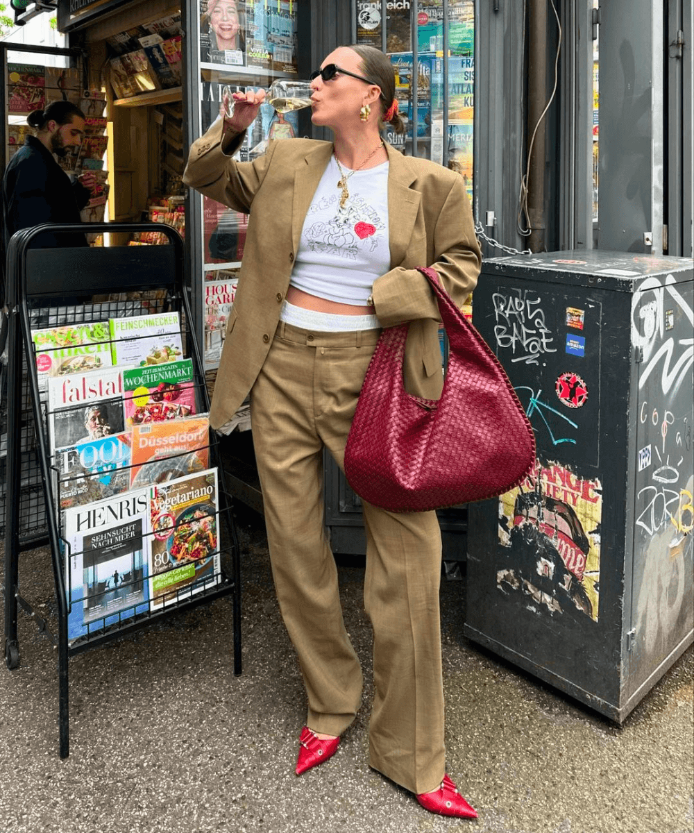 @lara_bsmnn - conjunto de alfaiataria, baby look, sapato e bolsa vermelha - cores de bolsa - outono - mulher em pé na rua usando óculos de sol e bebendo em um copo - https://stealthelook.com.br
