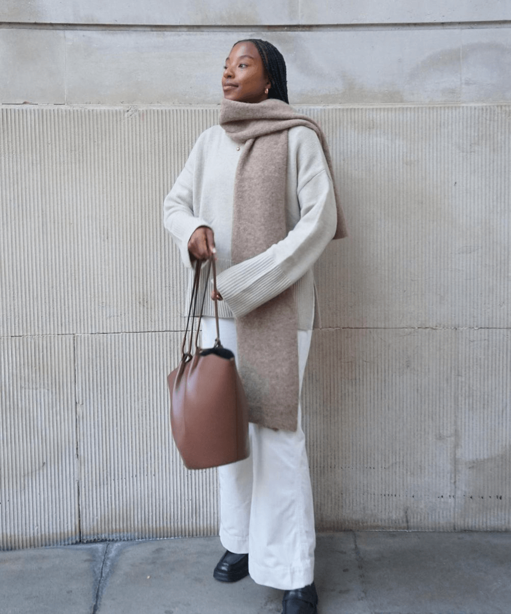 @taffymsipa - calça branca, tricot bege, cachecol longo e bolsa marrom - looks de frio - inverno - mulher negra em pé na rua - https://stealthelook.com.br