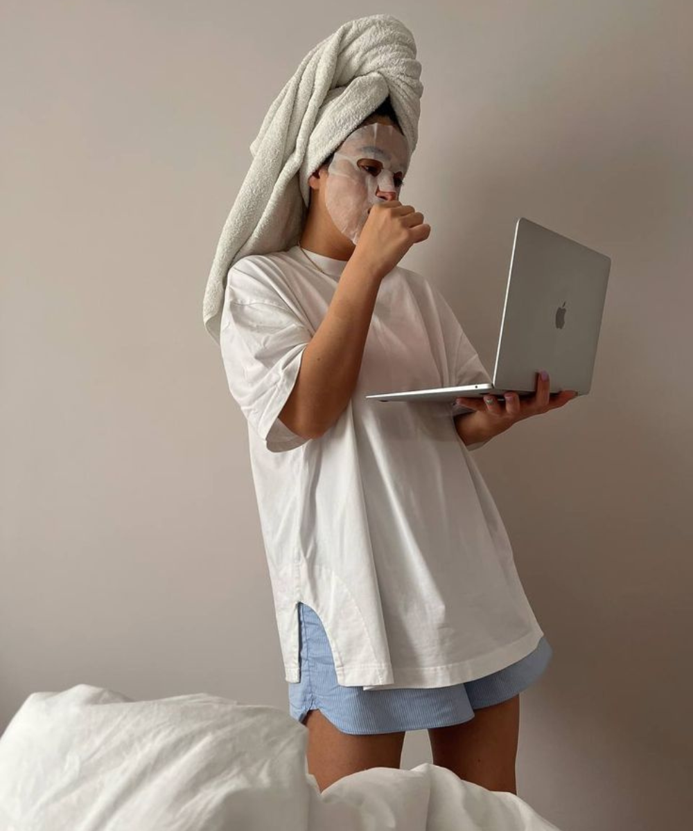N/A - Pijama - melhores filmes para ver - verão - mulher com toalha na cabeça e máscara de hidratação usando pijama enquanto segura um computador na mão - https://stealthelook.com.br