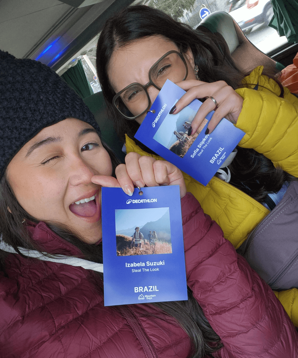 Sofi e Iza - roupas de inverno - neve - inverno - duas mulheres usando jaquetas de frio coloridas sorrindo para a foto e segurando um crachá de identidade azul - https://stealthelook.com.br