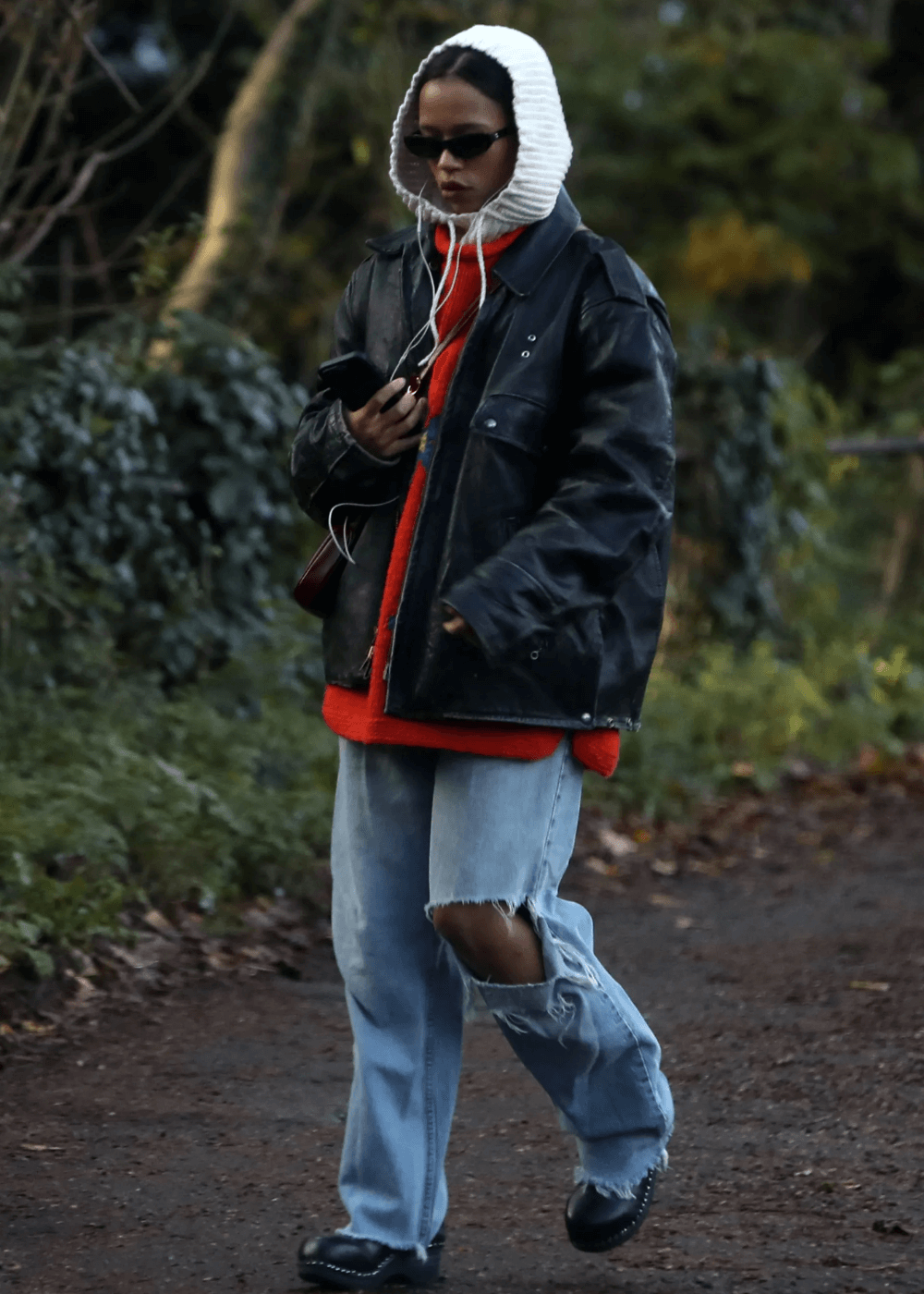 Taylor Russell - calça, trico vermelho, balaclava e jaqueta preta - Taylor Russell - inverno - mulher de óculos andando na rua - https://stealthelook.com.br
