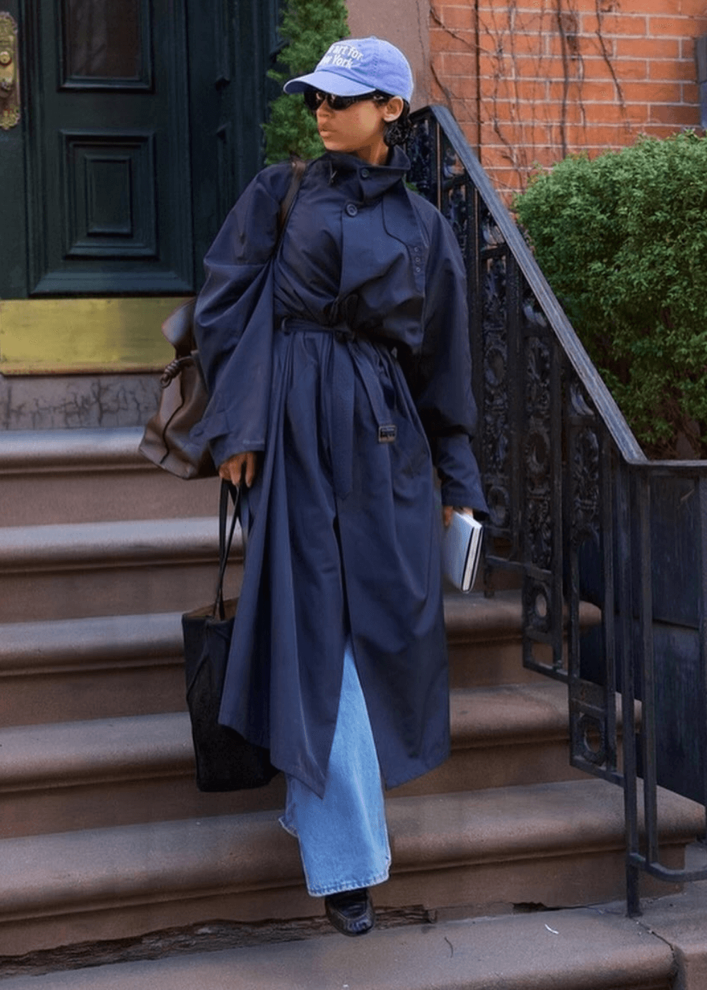 Taylor Russell - calça jeans, casaco trench coat azul e boné - Taylor Russell - inverno - mulher de óculos em pé na rua - https://stealthelook.com.br