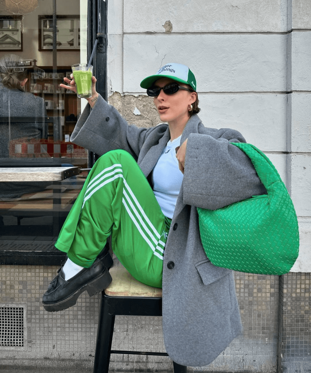 @lara_bsmnn - calça verde esportiva, tênis, blazer e óculos - outono 2024 - outono - mulher sentada em um banco com as pernas cruzadas - https://stealthelook.com.br